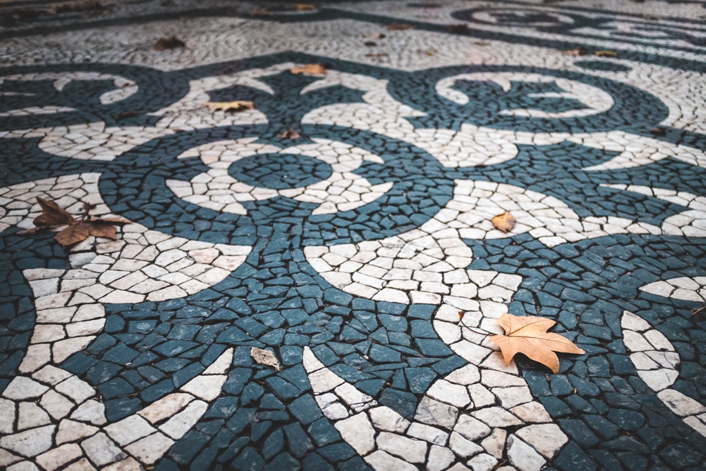 Detail of the beautiful Portuguese pavement at the Liberdade Avenue in the city of Lisbon, Portugal, with dry leaves; Concept for visit Lisbon in fall